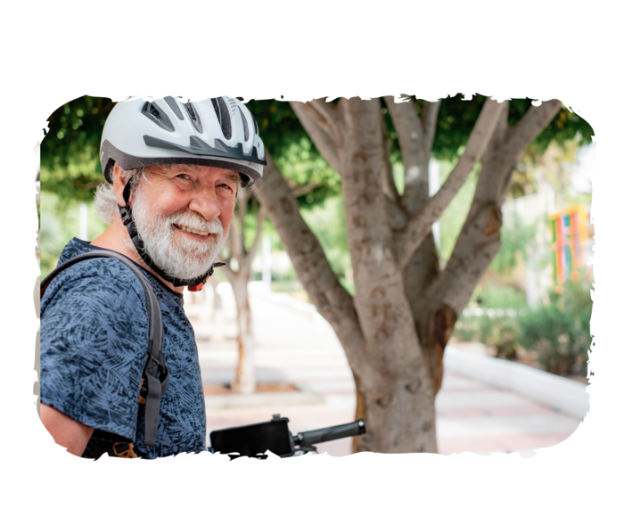 Ein älterer Mann mit Fahrradhelm lächelt in die Kamera. 