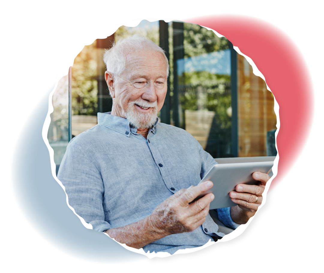 Ein älterer Mann schaut lächelnd auf ein Tablet.